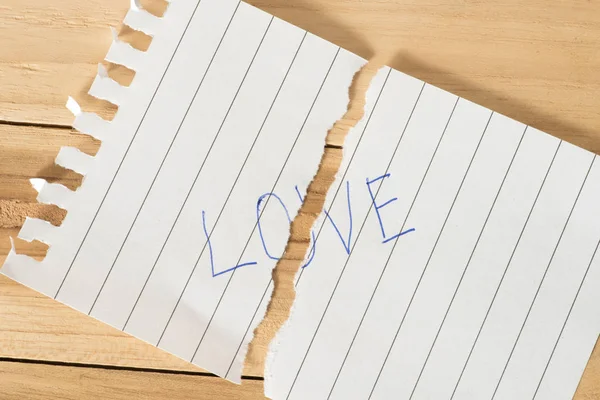 A piece of paper torn in the middle with the word love
