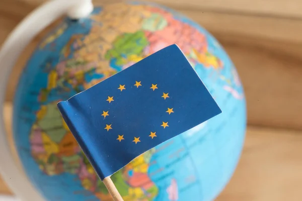 Σημαία Της Ευρωπαϊκής Ένωσης Και Μια Υδρόγειο Σφαίρα Στο Παρασκήνιο — Φωτογραφία Αρχείου