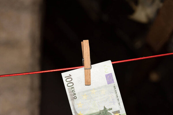 Счет в 100 евро на бельевой верёвке с прищепкой
