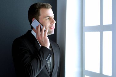 Modern ofiste cep telefonuyla konuşan yakışıklı iş adamı.