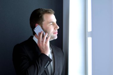 Modern ofiste cep telefonuyla konuşan yakışıklı iş adamı.