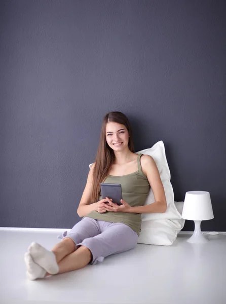 Mujer morena bonita sentada en el suelo con una almohada y mesa de avión — Foto de Stock