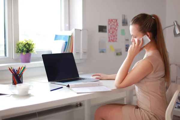 Jeune femme d'affaires assise au bureau et parlant au téléphone — Photo