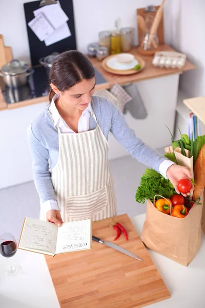 Жінка робить здорову їжу стоячи посміхаючись на кухні — стокове фото