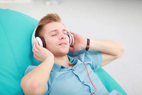 Een jonge knappe man op de bank luisterend naar muziek — Stockfoto