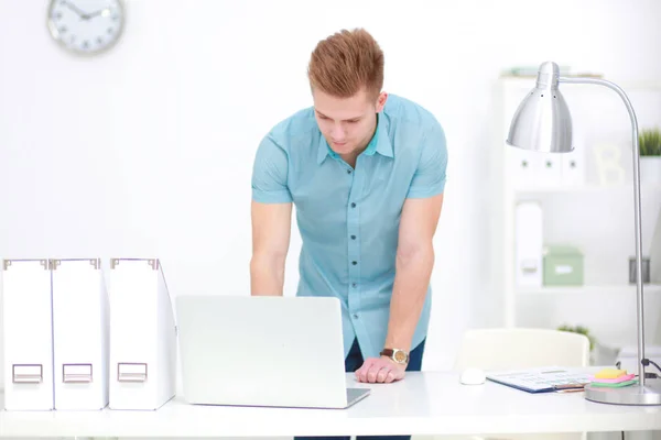 Ung affärsman arbetar på kontor, står nära skrivbord — Stockfoto