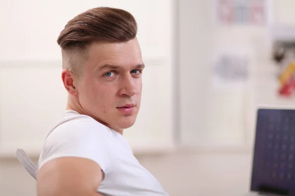 Young man sitting on chair with laptop — Stock Photo, Image