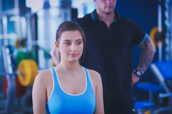 Beautiful woman at the gym exercising with her trainer. Beautiful woman. Gym