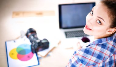Masada dizüstü bilgisayarla oturan kadın fotoğrafçı.