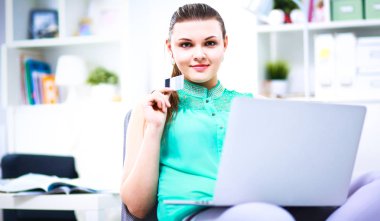 Elinde evrakları olan kadın masanın üstünde oturuyor.