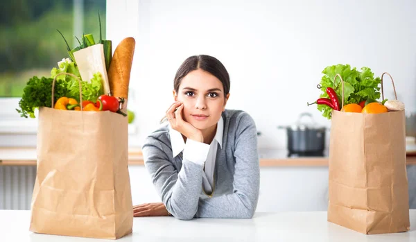 Young woman holding grocery shopping bag with vegetables Standing in the kitchen — Stock Photo, Image