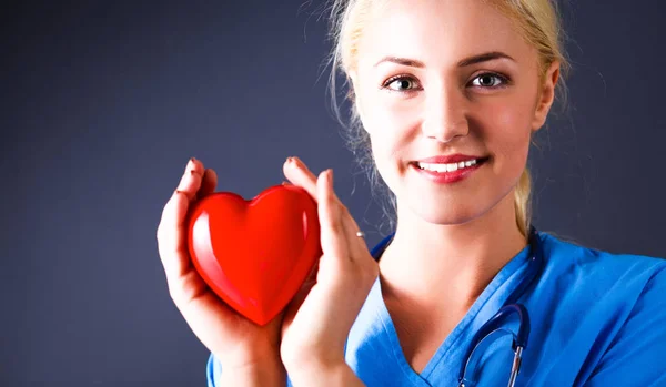 Молодая женщина-врач со стетоскопом держит сердце — стоковое фото