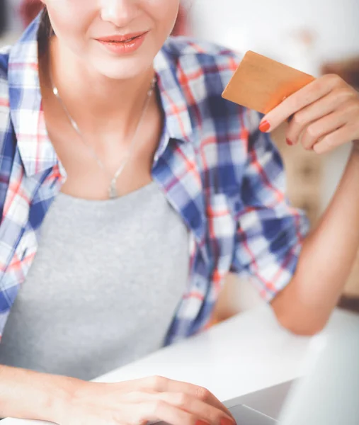 Femme souriante achats en ligne à l'aide d'un ordinateur et carte de crédit dans la cuisine — Photo