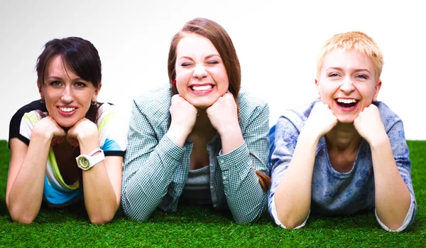 Четыре молодые женщины лежат на зеленой траве — стоковое фото