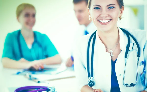 Bonito jovem sorridente médico feminino sentado na mesa — Fotografia de Stock