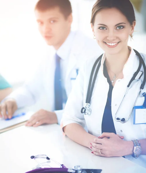 Hermosa joven sonriente doctora sentada en el escritorio — Foto de Stock