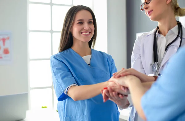 Médicos y enfermeras en un equipo médico apilándose las manos — Foto de Stock