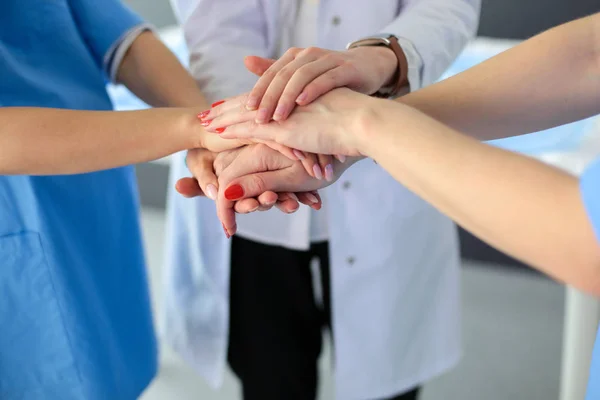 Médicos y enfermeras en un equipo médico apilándose las manos — Foto de Stock