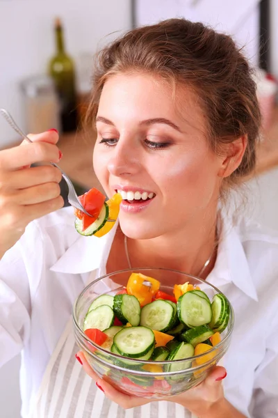 Sorrindo jovem mulher preparando salada na cozinha . — Fotografia de Stock