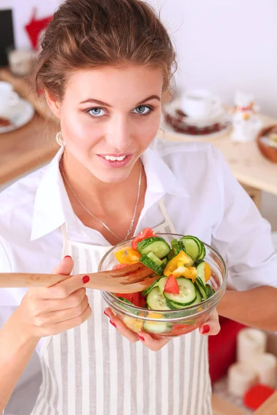 Usměvavá mladá žena připravuje salát v kuchyni. — Stock fotografie