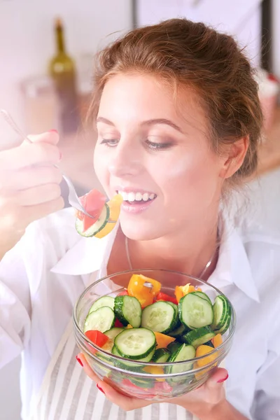 Mujer joven sonriente preparando ensalada en la cocina . — Foto de Stock