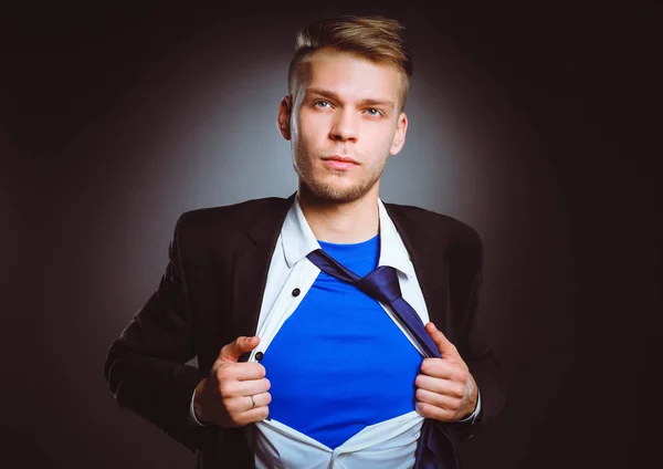 Joven hombre de negocios actuando como un súper héroe y rasgando su camisa, aislado sobre un fondo gris. Joven empresario — Foto de Stock