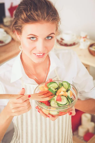 Jeune femme souriante préparant une salade dans la cuisine . — Photo