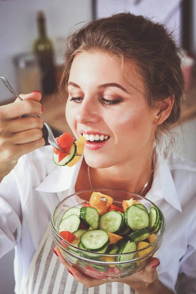 Mujer joven sonriente preparando ensalada en la cocina . — Foto de Stock