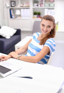 Elinde evrakları olan kadın masanın üstünde oturuyor.