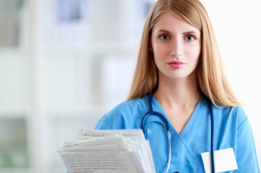 Hastane koridorunda klasörlü kadın doktor portresi.