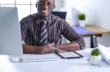 Yakışıklı Afro Amerikalı işadamı Klasik takım elbiseli bir dizüstü bilgisayar kullanarak ve ofiste çalışırken gülümseyen