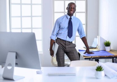 Ofiste bilgisayar ve planlarla çalışan Afrikalı Amerikalı bir mimar.