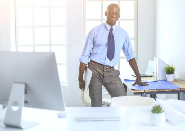 Ofiste bilgisayar ve planlarla çalışan Afrikalı Amerikalı bir mimar.