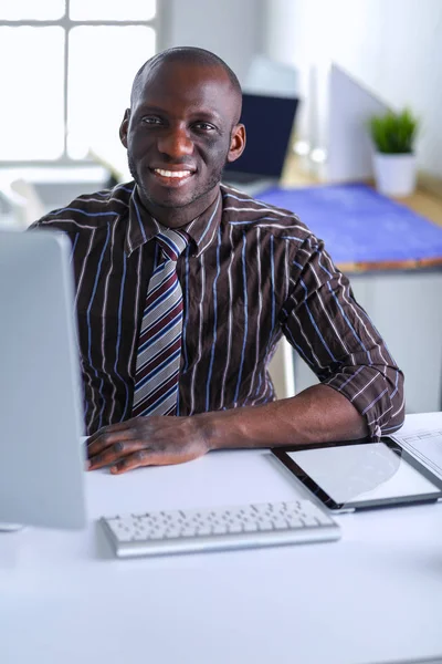 Guapo afroamericano hombre de negocios en traje clásico está utilizando un ordenador portátil y sonriendo mientras trabaja en la oficina —  Fotos de Stock