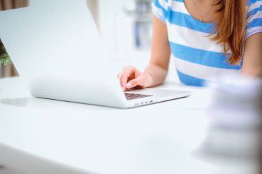 Elinde evrakları olan kadın masanın üstünde oturuyor.