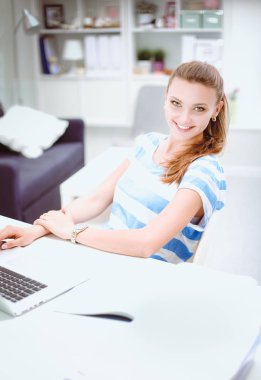 Elinde evrakları olan kadın masanın üstünde oturuyor.