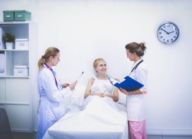 Genç bayan doktor hastanede steteskopla dikiliyor.