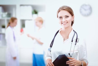 Genç bayan doktor hastanede steteskopla dikiliyor.