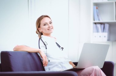 Hastanedeki kanepede oturan genç bir doktorun yakın plan portresi.