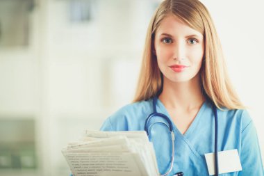 Hastane koridorunda klasörlü kadın doktor portresi.