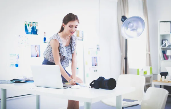 Portret van lachende jonge vrouw met camera zitten in loft appartement — Stockfoto