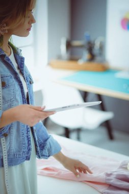 Moda tasarımcısı kadın stüdyoda tasarımları üzerinde çalışıyor.