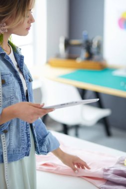 Moda tasarımcısı kadın stüdyoda tasarımları üzerinde çalışıyor.