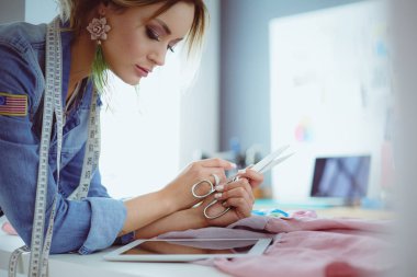 Moda tasarımcısı kadın stüdyoda tasarımları üzerinde çalışıyor.