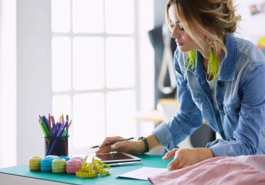 Moda tasarımcısı kadın stüdyoda tasarımları üzerinde çalışıyor.