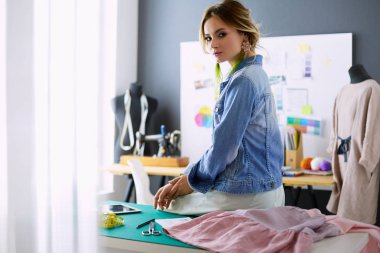 Moda tasarımcısı kadın stüdyoda tasarımları üzerinde çalışıyor.