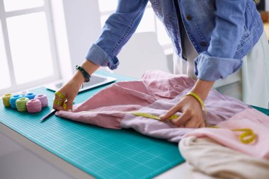 Moda tasarımcısı kadın stüdyoda tasarımları üzerinde çalışıyor.