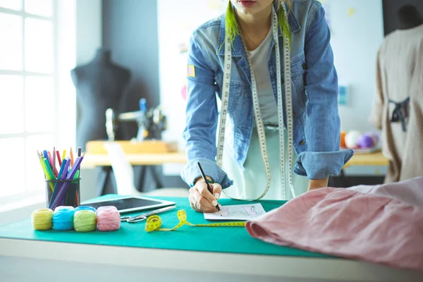 Moda tasarımcısı kadın stüdyoda tasarımları üzerinde çalışıyor.