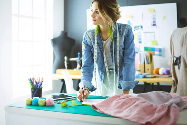 Moda tasarımcısı kadın stüdyoda tasarımları üzerinde çalışıyor.