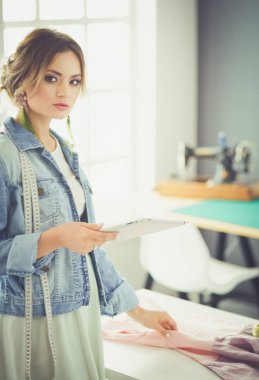 Moda tasarımcısı kadın stüdyoda tasarımları üzerinde çalışıyor.